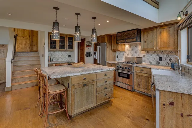 a kitchen with stainless steel appliances granite countertop a stove a sink dishwasher and a refrigerator with wooden floor