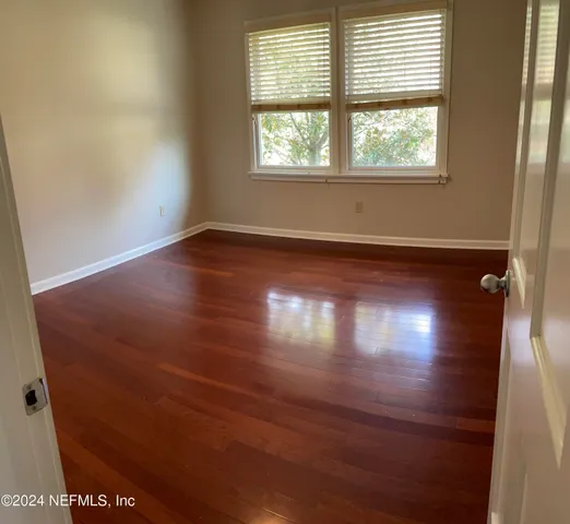 an empty room with wooden floor and windows in it