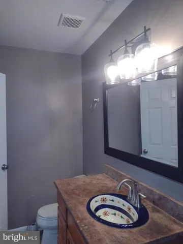 a bathroom with a granite countertop toilet a sink and a mirror