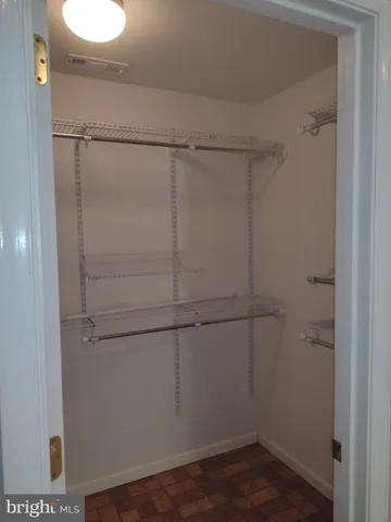 a walk in closet with wooden floor