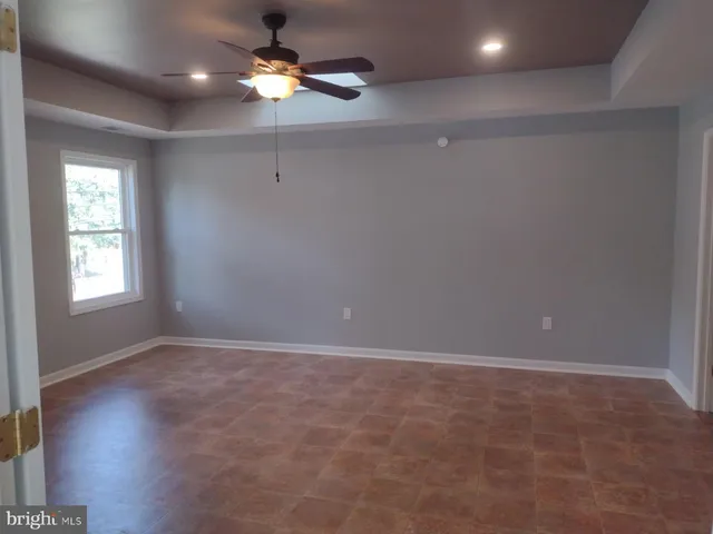 a view of an empty room with window chandelier fan and fire place