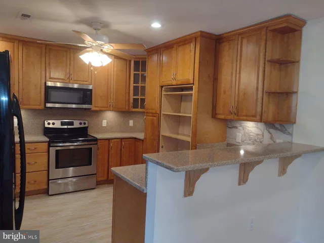a kitchen with kitchen island granite countertop stainless steel appliances and wooden cabinets