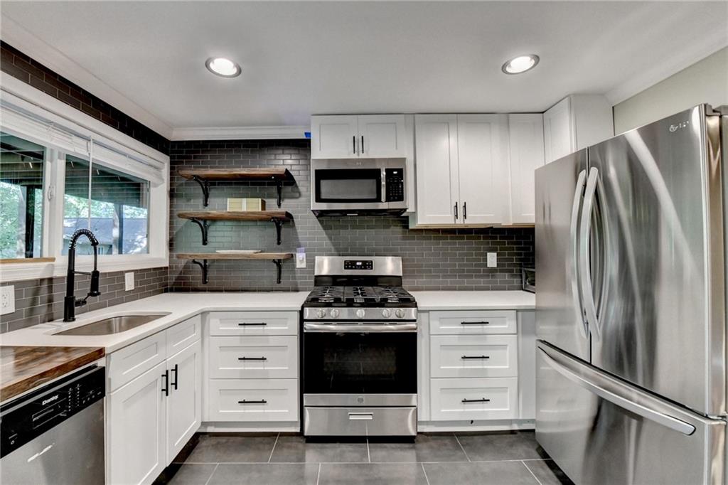 975 Timber Lake Trail Cumming, GA 30041 - Photo 54 of 82 a kitchen with white cabinets and stainless steel appliances