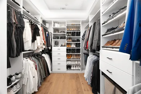 a view of walk in closet with clothes and shoes