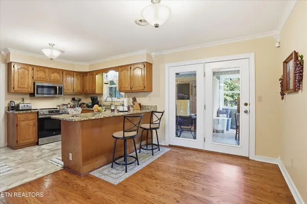 a kitchen with stainless steel appliances granite countertop a refrigerator oven a sink dishwasher a dining table and chairs with wooden floor