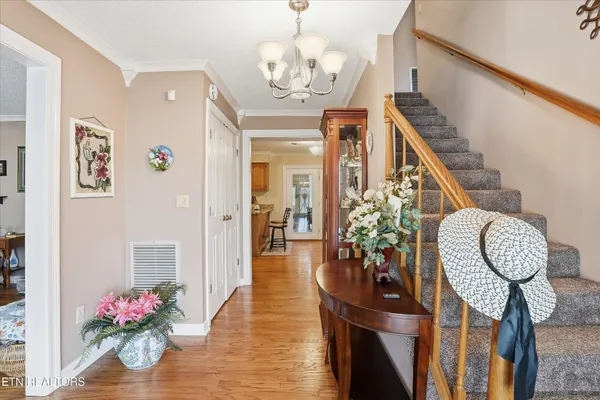 a view of a hallway to dining room with wooden floor chandelier and entryway