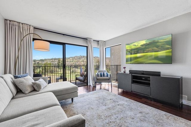 a living room with furniture a flat screen tv and floor to ceiling window