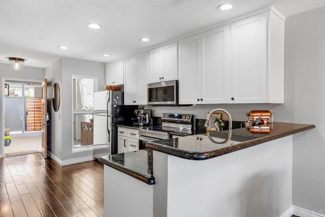 a kitchen with stainless steel appliances granite countertop a refrigerator a stove top oven a sink and dishwasher