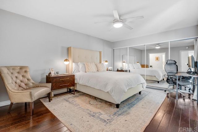a bedroom with furniture and a large mirror on dresser with wooden floor