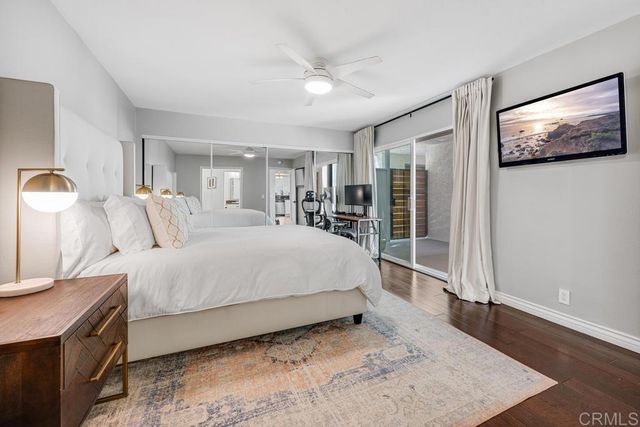 a spacious bedroom with a bed and a dresser with wooden floor