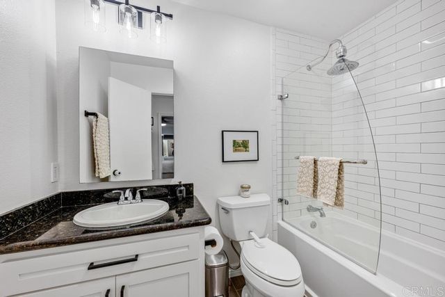 a bathroom with a granite countertop sink mirror toilet and bathtub