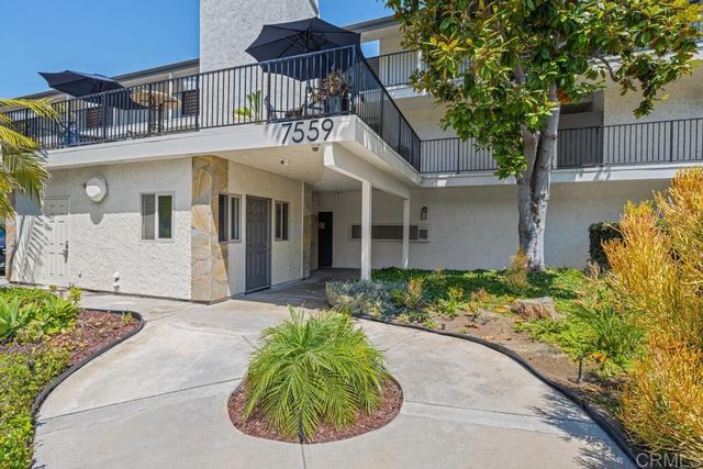 a view of a white house with large windows and plants