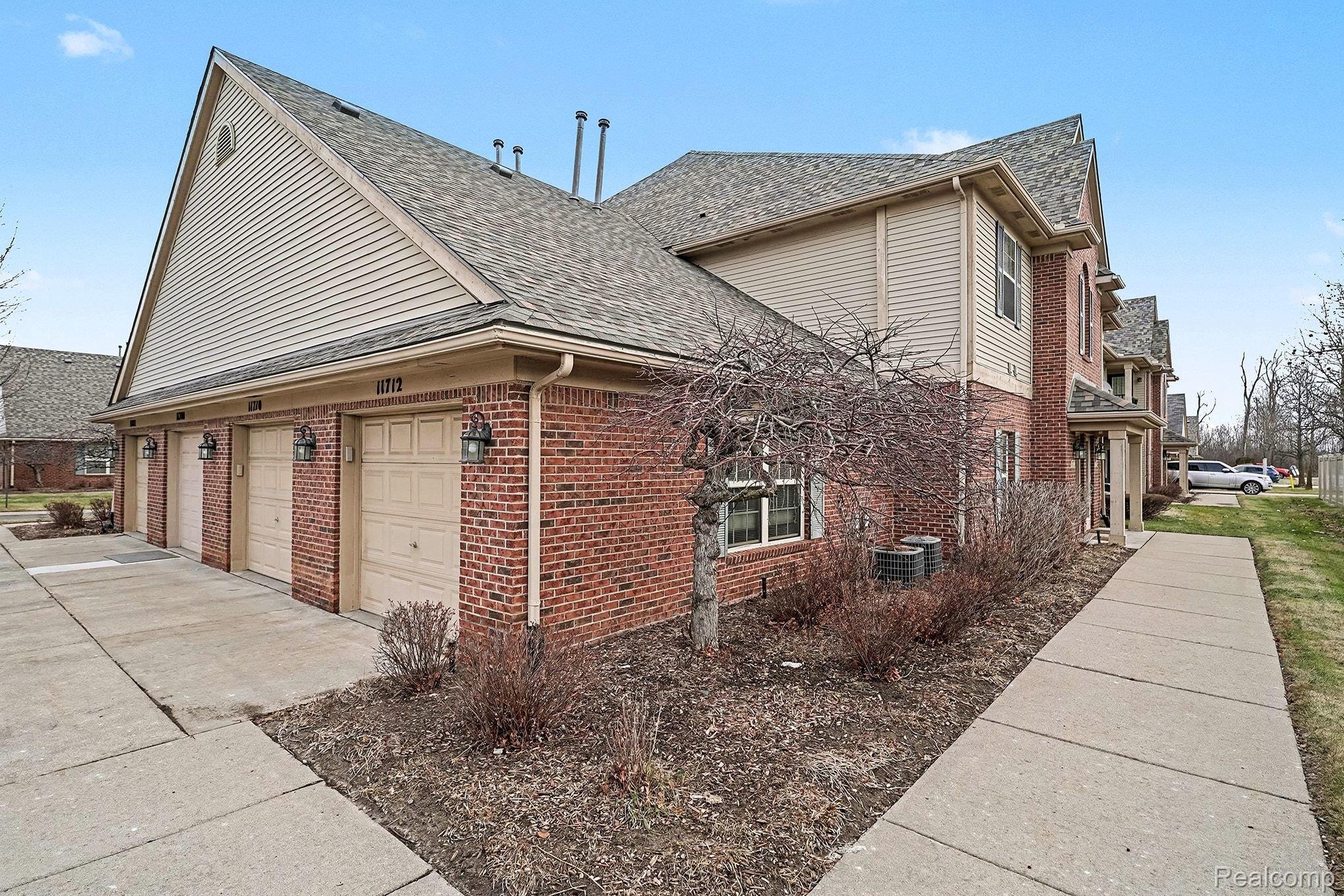 11712 Farmington Road Livonia, MI 48150 - Photo 12 of 13 View of side of home with an attached garage, brick siding, a shingled roof, and concrete driveway