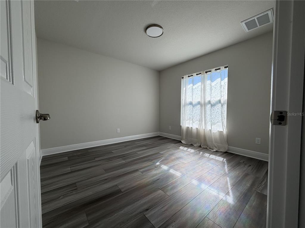 587 North Riva Ridge Path Inverness, FL 34453 - Photo 17 of 42 an empty room with wooden floor and windows