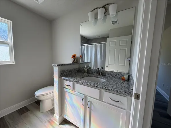 a bathroom with a granite countertop sink a toilet and a mirror
