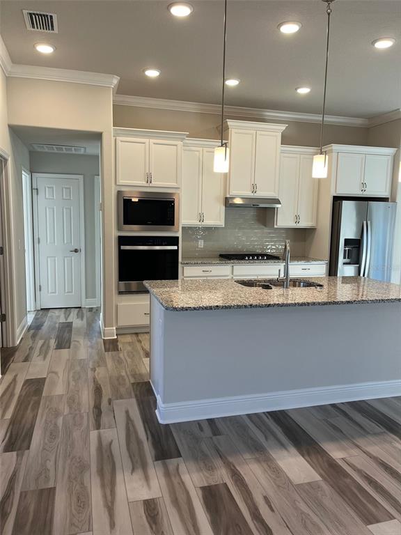 587 North Riva Ridge Path Inverness, FL 34453 - Photo 6 of 42 a large kitchen with stainless steel appliances kitchen island granite countertop a refrigerator a stove and a sink with wooden floor