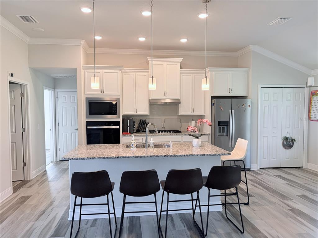 587 North Riva Ridge Path Inverness, FL 34453 - Photo 7 of 42 a kitchen with stainless steel appliances kitchen island granite countertop a table chairs sink and cabinets