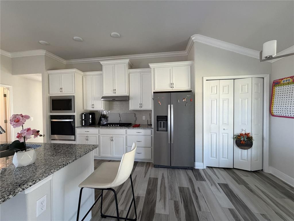 587 North Riva Ridge Path Inverness, FL 34453 - Photo 9 of 42 a kitchen with stainless steel appliances granite countertop a refrigerator oven a sink dishwasher and white cabinets with wooden floor