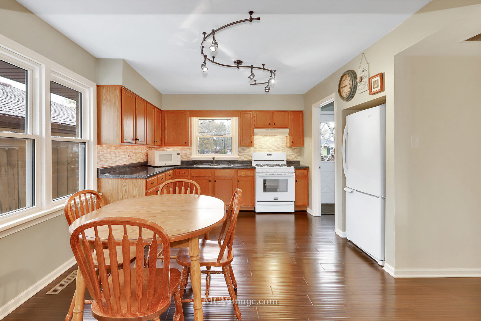 5830 108th Place Chicago Ridge, IL 60415 - Photo 13 of 28 a kitchen with granite countertop a refrigerator a stove a dining table and chairs with wooden floor