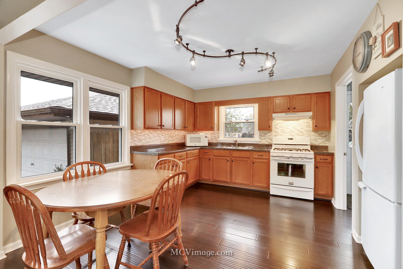 5830 108th Place Chicago Ridge, IL 60415 - Photo 10 of 28 a kitchen with granite countertop a stove a sink dishwasher a dining table and chairs with wooden floor