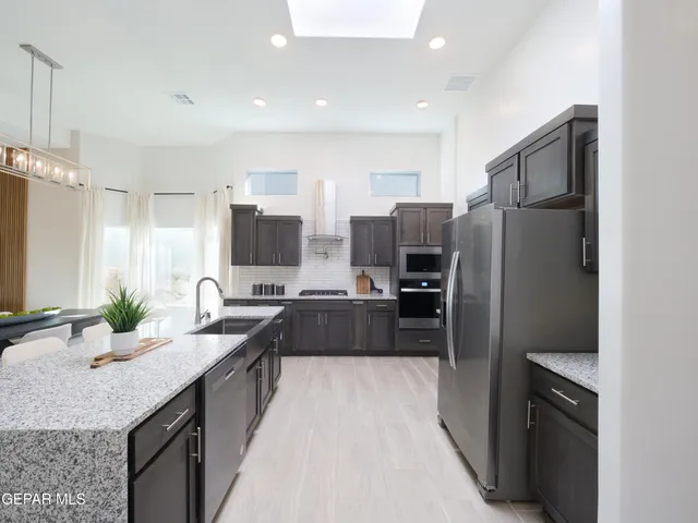 a kitchen with stainless steel appliances a dining table chairs stove refrigerator and cabinets