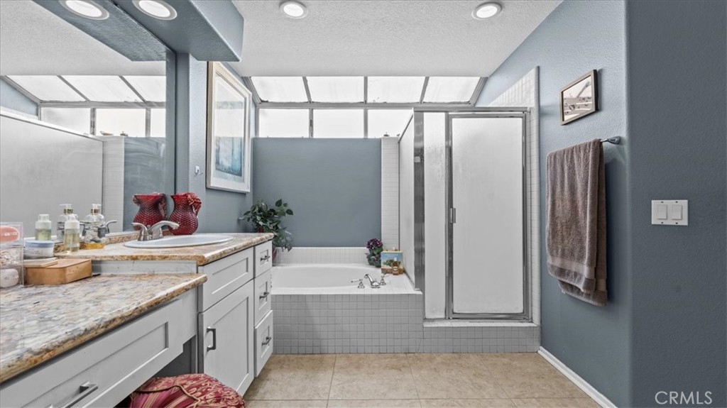 1671 Dominguez Ranch Road Corona, CA 92878 - Photo 22 of 42 The primary bath features dual vanities, a soaking tub, and a separate glass-enclosed shower, offering a spacious and functional layout.