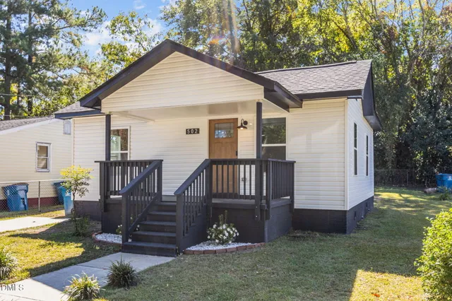 a front view of house with yard and trees in the background