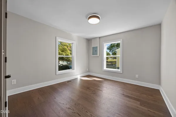 an empty room with wooden floor and windows