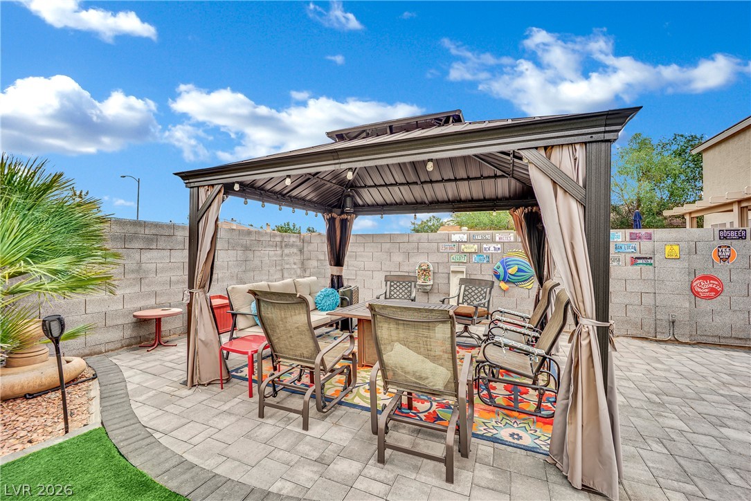 1724 Millstream Way Henderson, NV 89074 - Photo 38 of 60 A private backyard oasis features a shaded patio with string lights, perfect for outdoor relaxation and entertaining.