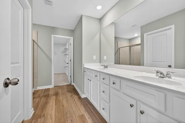 a spacious bathroom with a double vanity sink a mirror and shower