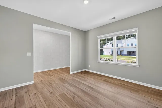 a view of an empty room with window and wooden floor