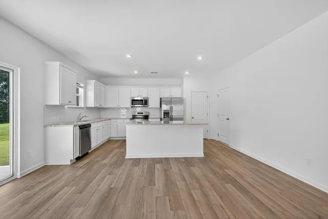 a large kitchen with a wooden floor and stainless steel appliances