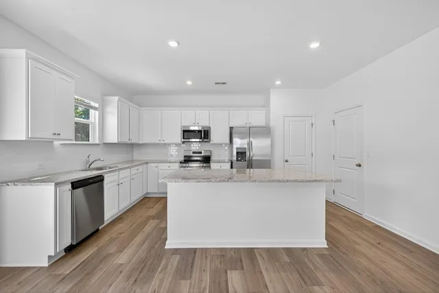 a large kitchen with stainless steel appliances granite countertop a stove a sink and a refrigerator