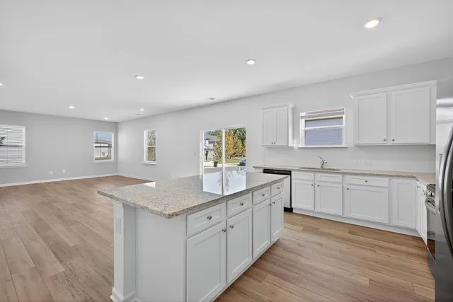 a kitchen with white cabinets granite counter tops and a stove