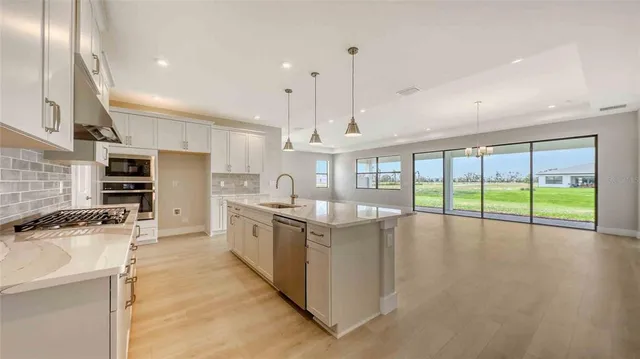 a large kitchen with stainless steel appliances granite countertop a lot of counter space and wooden floors