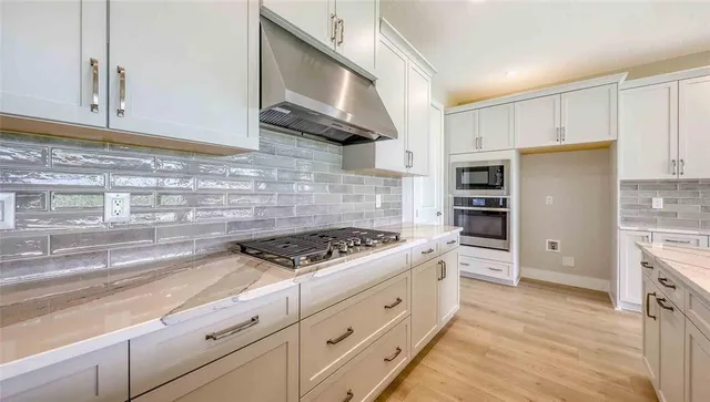 a kitchen with granite countertop cabinets stainless steel appliances and wooden floor