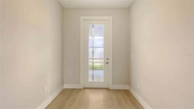 a view of an empty room with wooden floor and a window