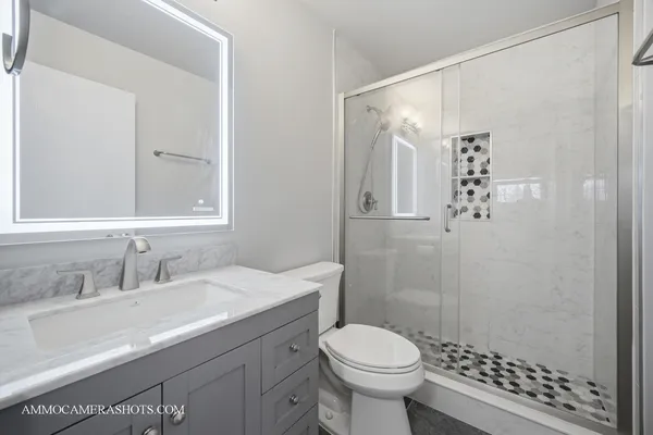 a bathroom with a sink toilet a mirror and shower