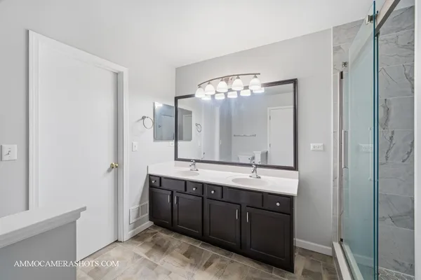 a bathroom with a double vanity sink mirror and shower