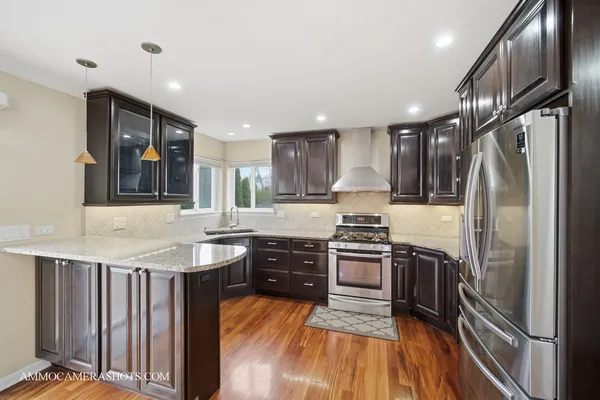a kitchen with stainless steel appliances granite countertop a refrigerator a stove and a sink