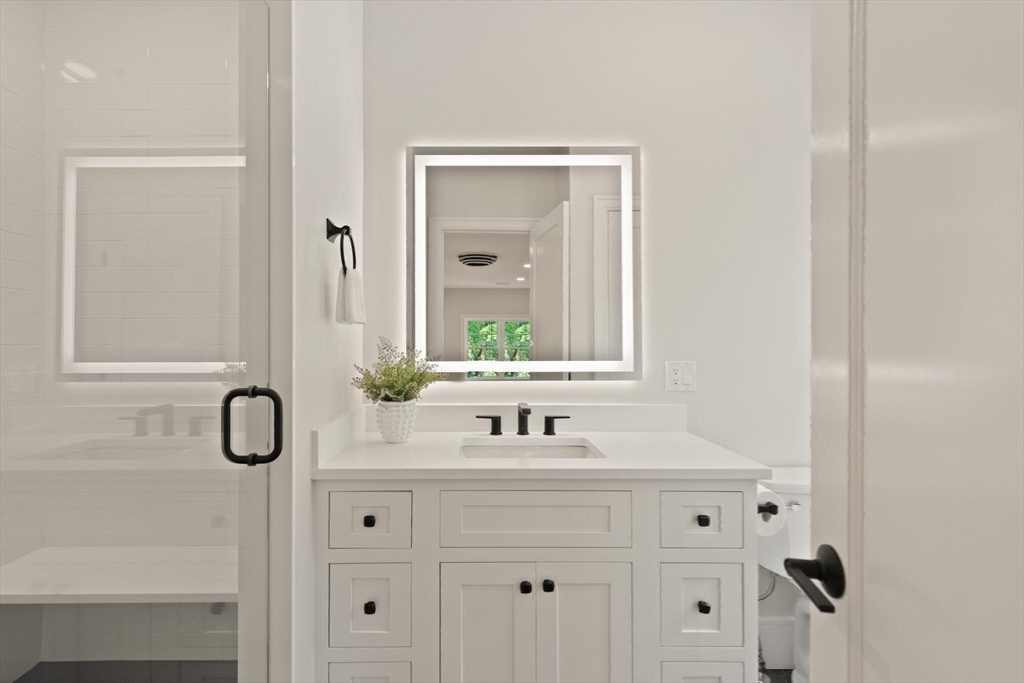 21 Columbus Street Lexington, MA 02421 - Photo 27 of 42 a bathroom with a granite countertop sink a toilet and mirror