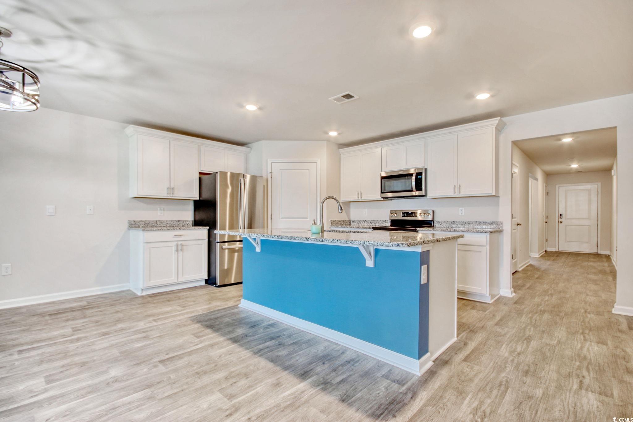 211 Seasons Trace Loop Longs, SC 29568 - Photo 12 of 37 Kitchen featuring stainless steel appliances, white cabinets, a kitchen bar, light wood-type flooring, and recessed lighting