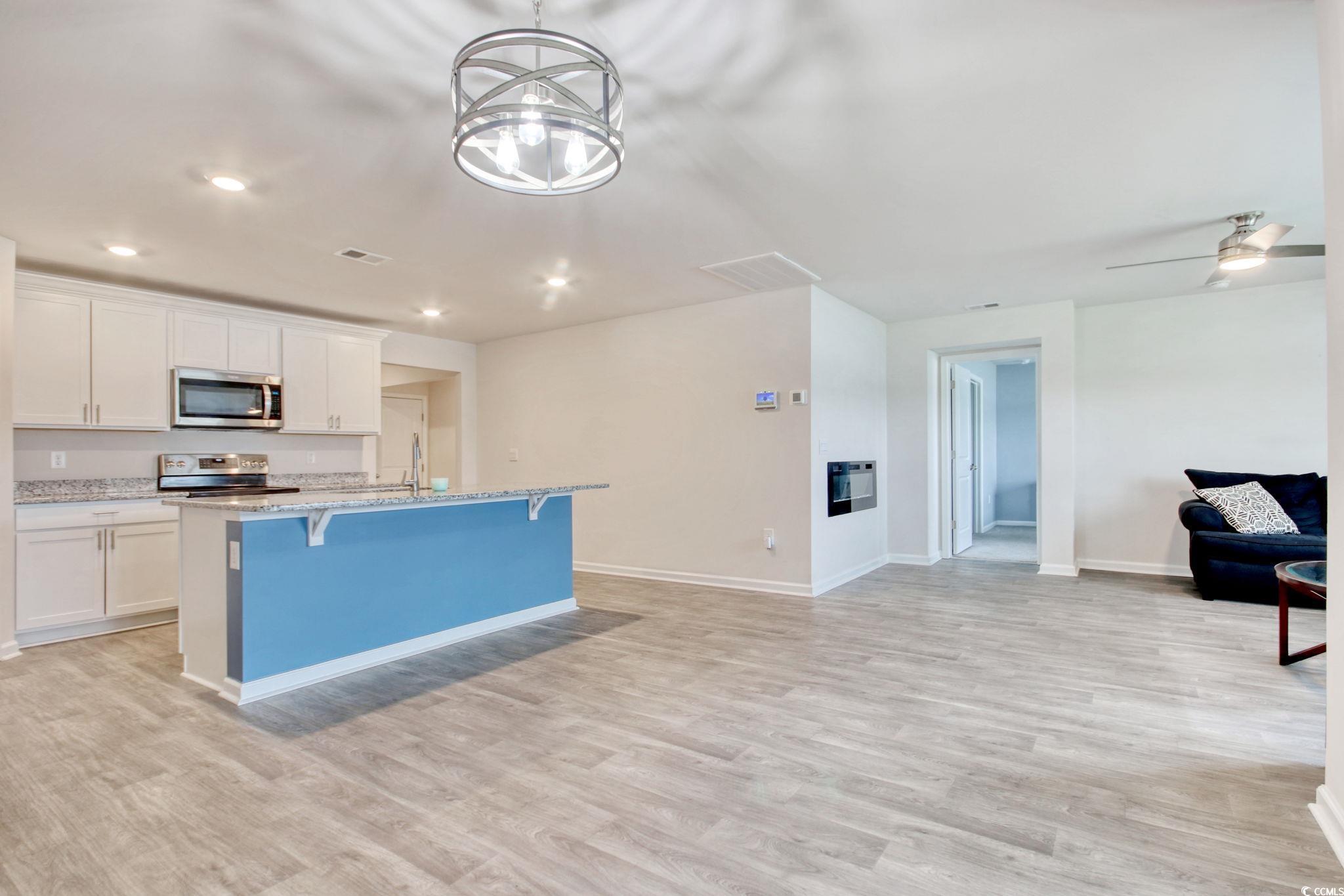 211 Seasons Trace Loop Longs, SC 29568 - Photo 36 of 37 Kitchen with stainless steel appliances, open floor plan, a kitchen island with sink, a breakfast bar, and white cabinets
