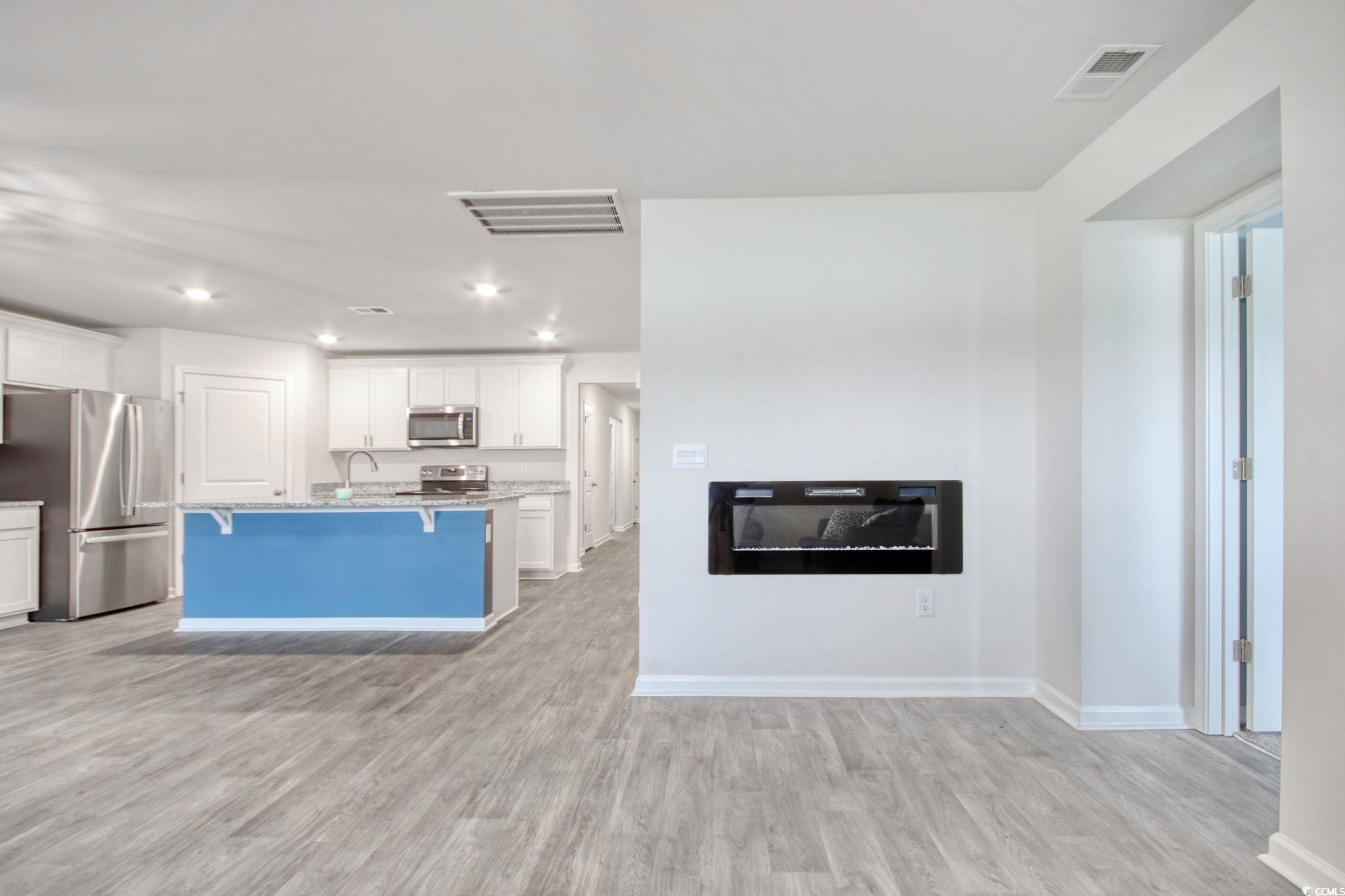 211 Seasons Trace Loop Longs, SC 29568 - Photo 37 of 37 Kitchen featuring appliances with stainless steel finishes, a kitchen breakfast bar, light wood-style flooring, white cabinets, and open floor plan