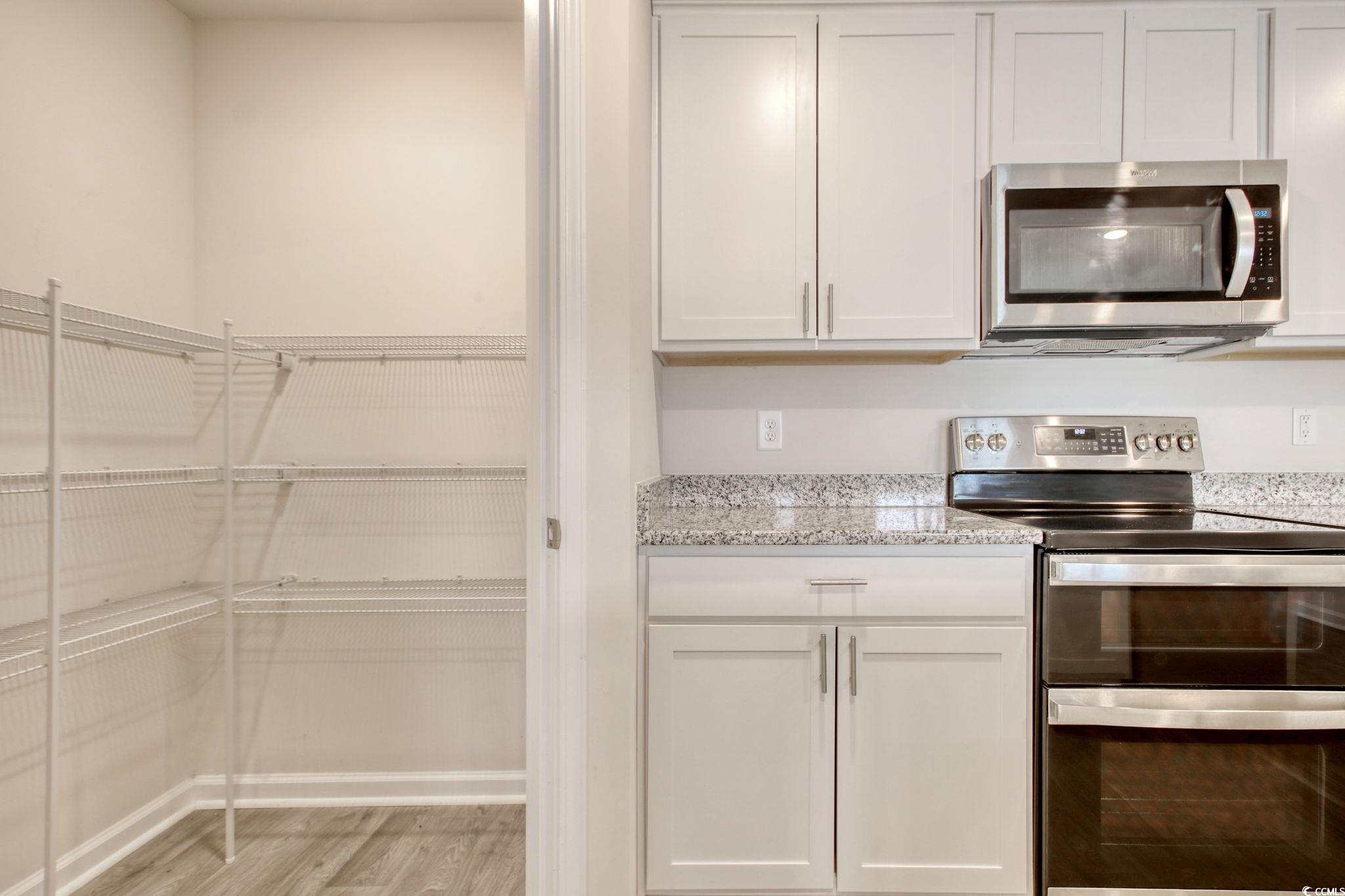 211 Seasons Trace Loop Longs, SC 29568 - Photo 14 of 37 Kitchen featuring stainless steel appliances, light wood finished floors, light stone counters, and white cabinetry