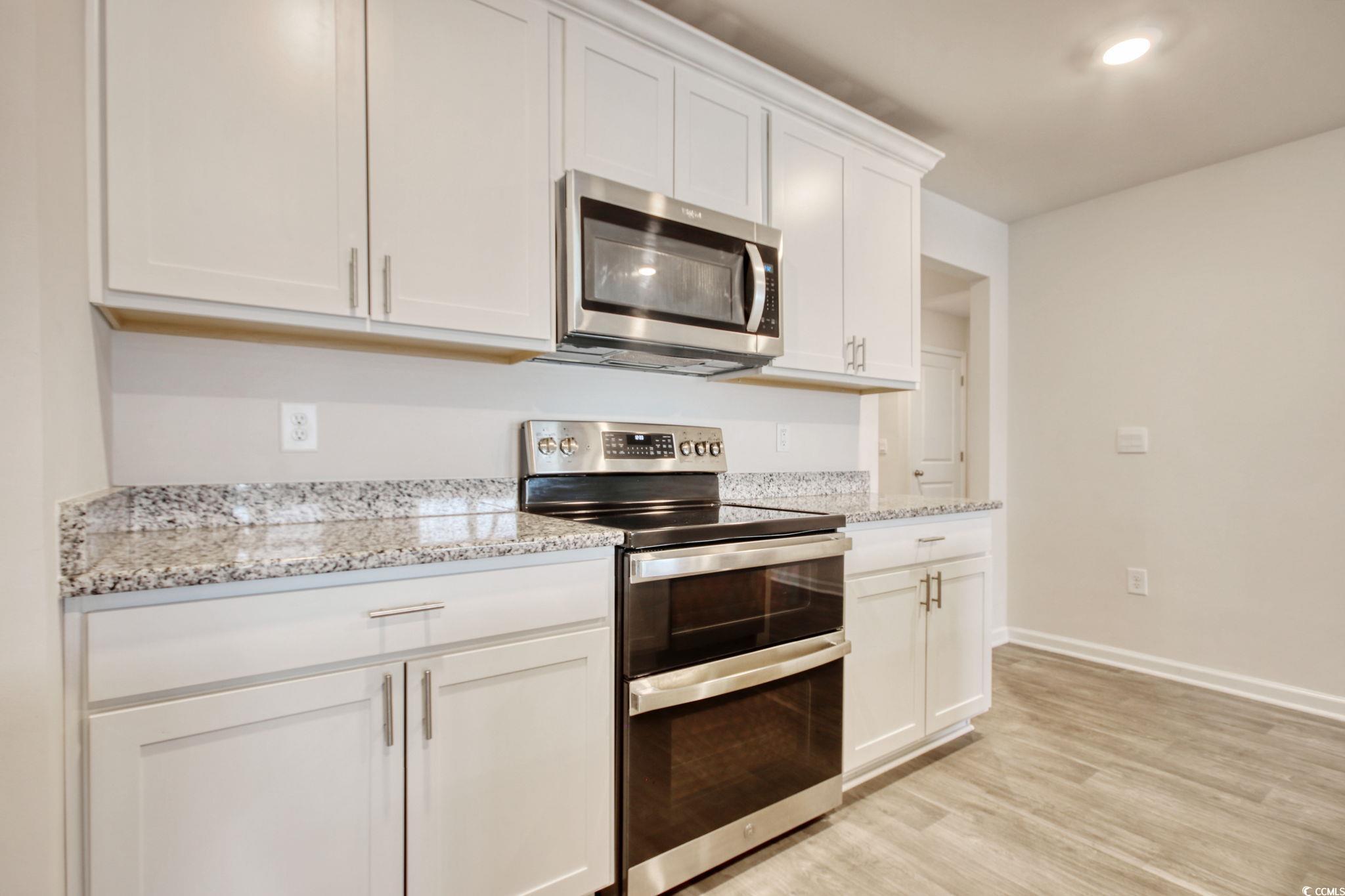 211 Seasons Trace Loop Longs, SC 29568 - Photo 10 of 37 Kitchen featuring stainless steel appliances, white cabinetry, light wood-style floors, and light stone countertops