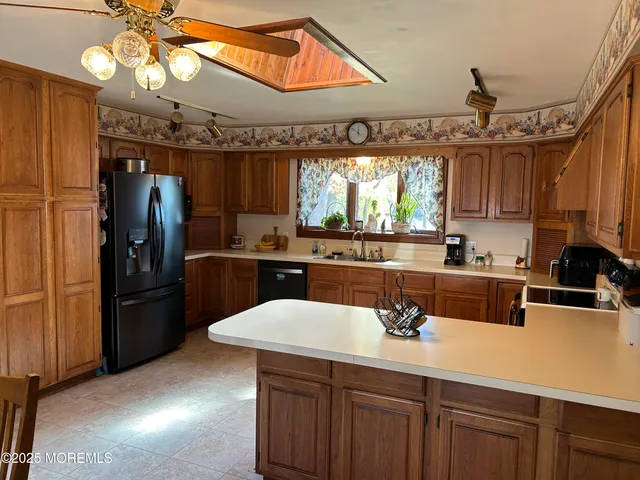 a kitchen with stainless steel appliances a sink a microwave a refrigerator and cabinets
