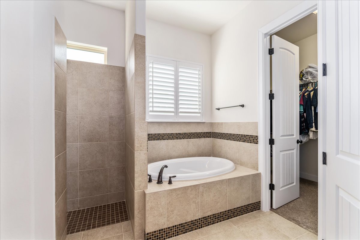 600 Garner Park Drive Georgetown, TX 78628 - Photo 11 of 39 Bathroom with a bath, light tile patterned flooring, a spacious closet, and a walk in shower