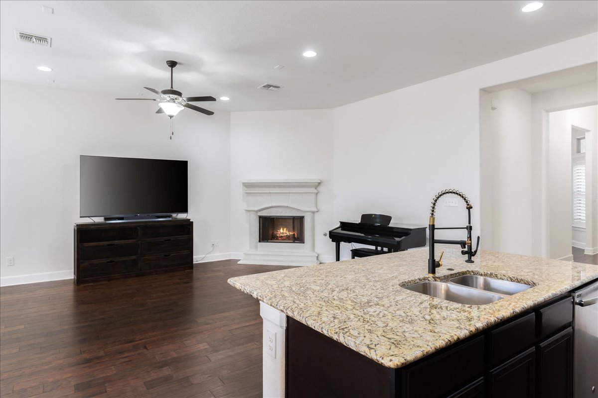 600 Garner Park Drive Georgetown, TX 78628 - Photo 38 of 39 Kitchen featuring open floor plan, a lit fireplace, recessed lighting, dark wood-type flooring, and a center island with sink