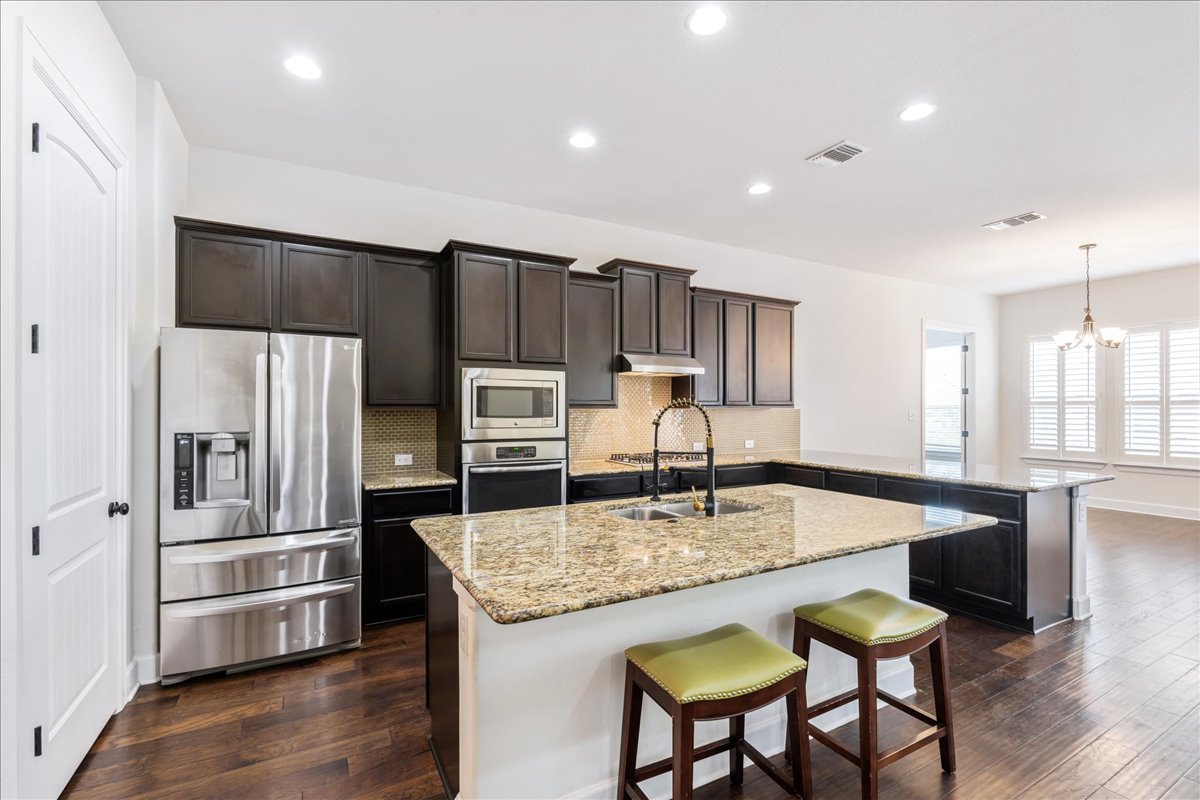 600 Garner Park Drive Georgetown, TX 78628 - Photo 19 of 39 Kitchen with a peninsula, stainless steel appliances, a kitchen breakfast bar, tasteful backsplash, and dark wood-style flooring